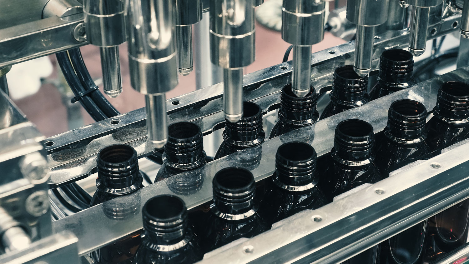 Bottles filling automation machine in modern factory.